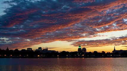 Wall Mural - sunset over a city with a lake and a clock tower