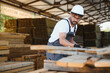 © Serhii - Carpenter working with wood planks in lumber warehouse