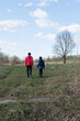 © Niko_Dali - Two people hike across a grassy field, enjoying a sunny day outdoors. A lone tree stands in the distance.