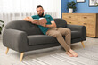 © New Africa - Harmony. Man reading book on sofa at home