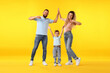 © New Africa - Happy family. Parents giving high five and their son on yellow background