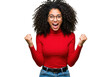 © Over View - A cheerful young woman with curly hair, isolated on transparent background, celebrates with excitement, wearing a red sweater and glasses