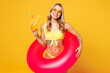 © ViDi Studio - Young beautiful sexy woman wears bikini swimsuit sunglasses rest near hotel pool hold pink rubber ring drink citrus cocktail isolated on plain yellow background. Summer vacation sea sun tan concept.