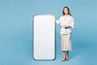 © ViDi Studio - Full body young employee business woman corporate lawyer she wear shirt classic formal clothes work in office point finger on big huge blank screen mobile cell phone isolated on plain blue background.