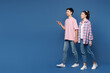© ViDi Studio - Full body sideways young couple two friends family man woman they wear pink casual clothes together walk go point index finger aside on area isolated on plain blue background studio Lifestyle concept