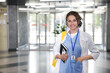 © New Africa - Medical student in uniform with notebook and smartphone indoors, space for text