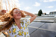 © Westend61 - Woman enjoying a sunny day on a rooftop with solar panels
