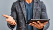 © Dreamer Studio - Professional man in textured gray blazer holding tablet in one hand while gesturing openly in modern neutral background business setting