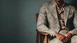 © Dreamer Studio - Stylish man in light-colored suit with open-collar shirt seated in wooden chair against muted green background in warm editorial lighting