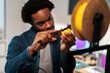 © Studio Marmellata - An African American man precisely measures yellow 3D printer filament with a caliper. He focuses intently on the task, ensuring accuracy for his engineering or design project.