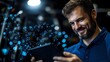 © Yuliia - Caucasian bearded man in blue polo shirt smiling while using digital tablet with glowing network visualization effect, illuminated by dramatic lighting in dark environment.