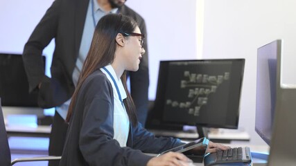 An Asian female developer and an Indian male colleague collaborating on a project. A senior programmer mentors a junior developer in a modern tech office at night.