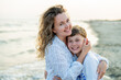 © Kristina89 - Young mother with little daughter near the sea. Beach with sand. Blue water.