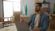© Krakenimages.com - Young hispanic man in casual clothes works on laptop surrounded by moving boxes in new home living room setting.