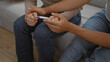 © Krakenimages.com - Couple sitting together on a couch in their home holding a pregnancy test, symbolizing love, anticipation, and new beginnings in a warm, intimate indoor setting.
