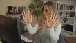 © Krakenimages.com - Woman with blonde hair wearing glasses hands raised with palms out at computer desk in office; refusal frustration.