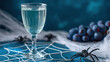 © Moonroad - Halloween craft drink setup with clear glass on spider web decoration surrounded by plastic spiders and dark grapes creating spooky festive atmosphere