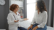 © Krakenimages.com - Doctor consulting patient in hospital room with both women engaged in healthcare discussion, highlighting indoor clinic setting and medical professional interaction.
