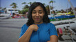 © Krakenimages.com - Woman wearing blue shirt smiling and pointing finger to chest on street near docked boats and palm trees; self reflection.