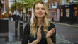 © Krakenimages.com - Woman clapping on street with blonde hair smiling in an urban city center showing vibrant city life and energy with colorful urban landscape and people in the background.