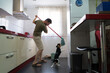 © ADDICTIVE STOCK - Man cleaning kitchen while playful dog interacts