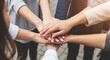 © Zabi - A diverse group of people join hands together in a show of unity and teamwork
