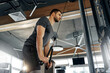 © Valerii Apetroaiei - Young athletic man training triceps using rope attachment on cable machine in a modern gym. Intense concentration during upper body strength workout. Concept: fitness, strength, motivation, discipline