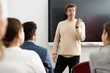 © JackF - Friendly business coach answering questions from listeners sitting at desks at seminar in advanced training