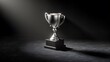 © apisit - Elegant trophy under spotlight: A captivating image of a gleaming silver trophy, dramatically lit against a dark, textured background, evoking a sense of prestige and achievement.