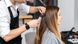 © fara - Professional male hairdresser styling a woman's long, brown hair in a modern salon. Focus on the hands, comb, and hair during a beauty treatment or cut.