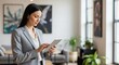 © An - A businesswoman in a suit using a tablet in an office setting.