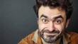 © AdamDiezel - Handsome man with a funny facial expression, smiling and looking at the camera, isolated on a grey background with copy space.