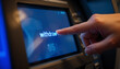 © Nan_Stock - A person's finger pressing the 'withdraw' button on an ATM touchscreen interface.