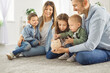 © Studio Romantic - Portrait of happy family of mother, father and kids putting money coin into piggy bank sitting on floor in living room at home together. Family savings, investment and money management concept.