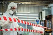 © BESTIMAGE - Man inspector scientist investigate chemical gas leak spill with safety face mask PPE suit in area closed barricade security red white tape. danger area infected toxic leak spill cross stripe ribbon