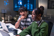 © Leny Studio - Two programmer developers collaborate in office environment focusing on code development with laptops and digital screens, showing concentration and teamwork in modern workspace