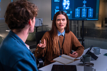 programmer and developer discuss code in office setting with digital screen showing flowchart while 