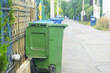 © tanyatorgonskaya - City services work: waste removal from households. Plastic containers for separate garbage collection on the street in a residential area. A close-up of a green trash bin with an open lid