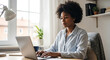 © Yasin - Woman typing on laptop at desk with plant and lamp office