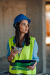© Ljustina - Female engineer using smartphone and holding clipboard on construction site
