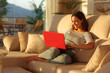 © Antonioguillem - Happy woman at sunset using red laptop at home