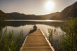 © Westend61 - Woman meditating on jetty over lake by mountain range
