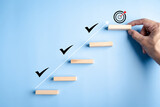 Business growth success and achievement with hand arranging wooden steps and check marks, goal setting, progress tracking, and personal development.