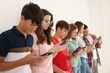 © New Africa - Teenagers with smartphones near white wall indoors