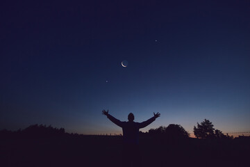 Wall Mural - silhouette of a man and countryside under the moon, stars and planets in blue hour time.