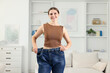 © New Africa - Beautiful woman wearing old jeans after weight loss indoors