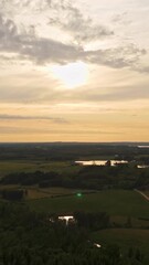 Wall Mural - vertical shot of a lush green landscape beneath a cloudy sky lit by soft yellow sunlight