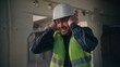 © Yuliia - Caucasian builder worker man guy male handyman engineer architect in hardhat employee closing ears with hands industrial loud explosion in construction factory hiding from demolition building noise
