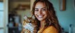 © Yuliia - Young woman with long brown wavy hair wearing yellow sweater holds fluffy ginger Maine Coon cat while smiling warmly at home, lifestyle portrait with natural lighting.