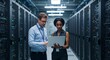 © rdkcho - Two Diverse IT Professionals Collaborate on a Laptop in a Modern Server Room Data Center